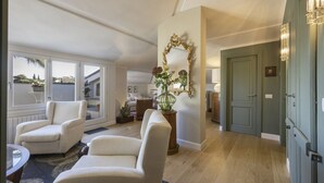 Een ruime woonkamer met een groot raam, een spiegel en een deur naar een andere kamer.