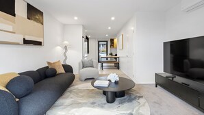 Una sala de estar moderna con sofá, mesa de centro y televisor.