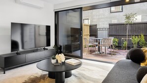 Una sala de estar moderna con un televisor de pantalla plana, un mueble de entretenimiento negro y una mesa de centro redonda.