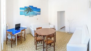 Ein Wohnzimmer mit einem runden Holztisch, einem weißen Sofa und einem gemusterten Teppich.