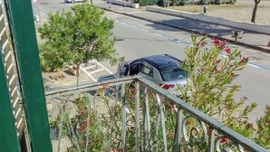 Eine Küstenstraße mit geparkten Autos, einem Fußweg und Blick auf das Meer.