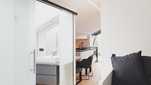 Ein modernes Interieur mit einer Schiebetür zu einer Küchenzeile, einem Esstisch und einem Sofa.
