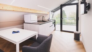 Eine moderne Küche mit integriertem Geschirrspüler, einer kleinen Essecke mit Tisch und Stühlen sowie einer großen Glasschiebetür, die auf einen Balkon mit Außenblick führt.