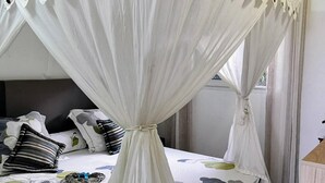 A four-poster canopy bed with a white canopy and a floral bedspread.
