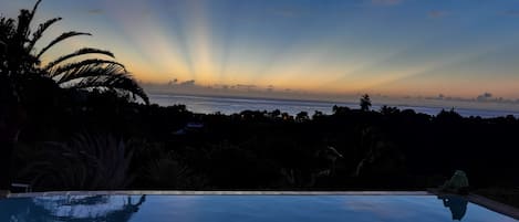 A pool with a view of the ocean at sunset.