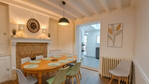 A dining area with a wooden table, six chairs, a fireplace, and a modern pendant light. - Cosy 5-bedroom townhouse. Close to all shops and hypercentre! (LE MANS)