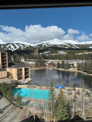 A view of a mountain with snow-capped peaks, a body of water, and a building complex with multiple floors and balconies. - Best Resort Breckenridge, CO- Luxurious 2BD/2BA Condo with fitness room, WiFi (Breckenridge)