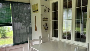 Un coin repas avec une table et des chaises blanches, un ventilateur de plafond et des décorations sur le thème de la pêche.