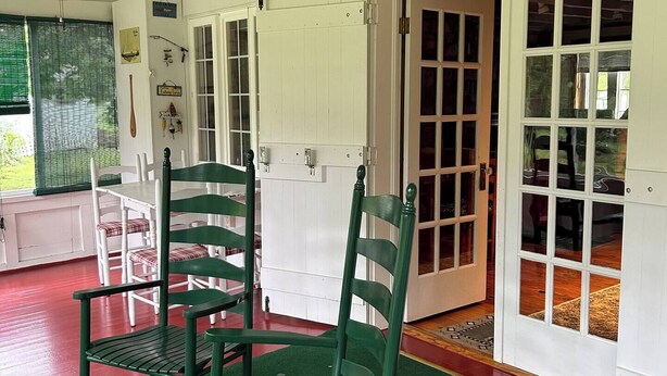 Une pièce avec une moquette verte, des murs blancs et une pancarte sur laquelle on peut lire : « Bienvenue au Cottage ».