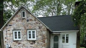 Une maison en pierre avec un porche en bois et une pancarte indiquant «Bienvenue».