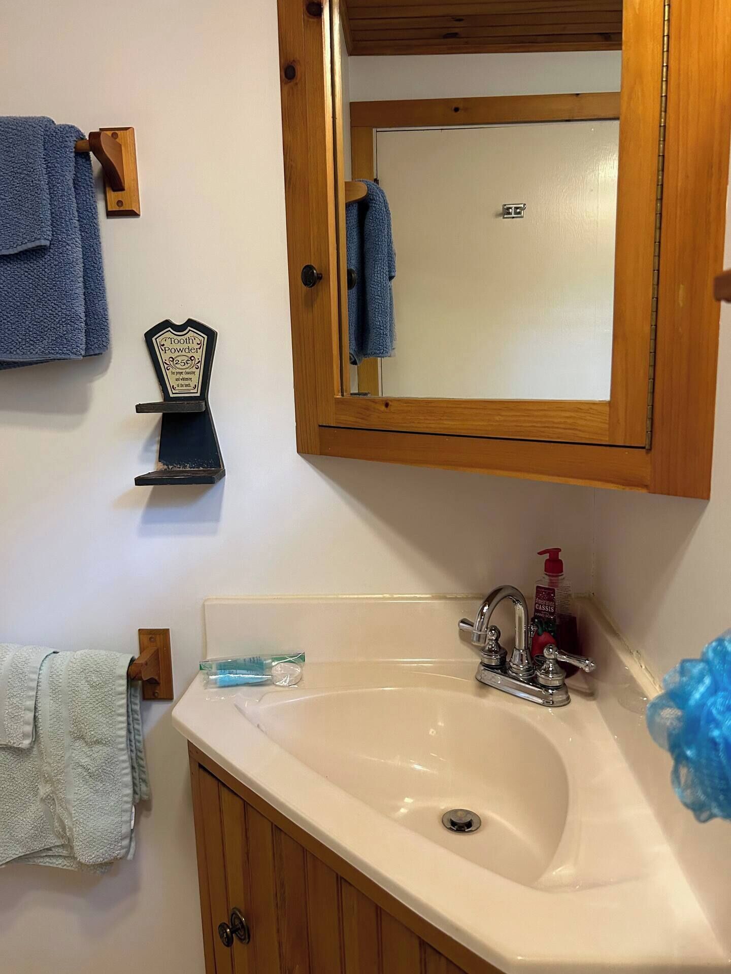 Une salle de bain avec un meuble en bois, un lavabo, un miroir et des serviettes.