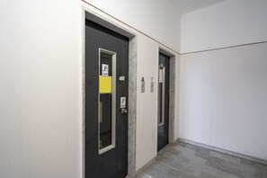 Un couloir avec deux portes, dont une est signalée comme étant accessible aux personnes à mobilité réduite et l’autre est réservée à un usage général.