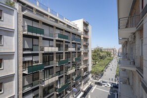 Un immeuble résidentiel à plusieurs étages, doté de balcons, donnant sur la rue et offrant une vue sur un ciel dégagé.