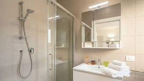 Une salle de bain moderne avec une douche à parois de verre, un meuble-lavabo blanc avec un miroir et un évier.