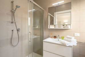 Une salle de bain moderne avec une douche à parois de verre, un meuble-lavabo blanc avec un miroir et un évier.
