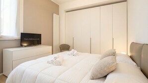 Une chambre à coucher avec un lit, un téléviseur posé sur une commode, un radiateur et une armoire.