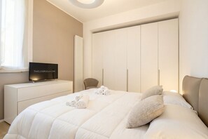 Une chambre à coucher avec un lit, un téléviseur posé sur une commode, un radiateur et une armoire.