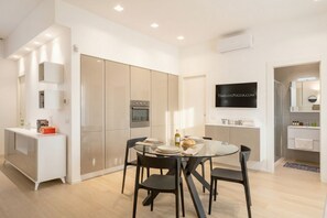 Une cuisine moderne avec un coin repas, un four encastré et un téléviseur fixé au mur.