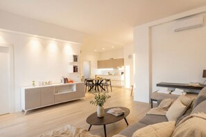 A modern living room with a sofa, a coffee table, and a dining area with a table and chairs. -  Central Station Apartment – Modern Comfort in the Heart of Bari (Bari)