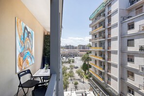 Ein Balkon mit Tisch und Stühlen, mit Blick auf eine Skyline mit Gebäuden und einem Platz.