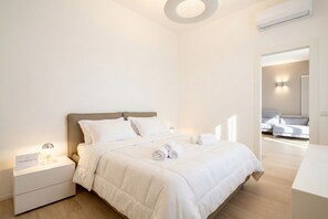 Une chambre à coucher moderne avec un lit, une table de chevet et une vue sur une autre pièce.