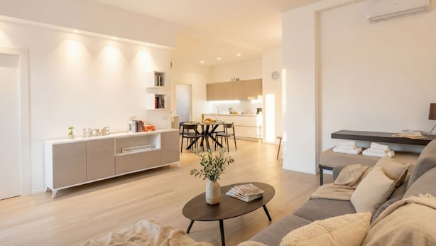 A modern living room with a sofa, a coffee table, and a dining area with a table and chairs. - Central Station Apartment – Modern Comfort in the Heart of Bari (Bari)