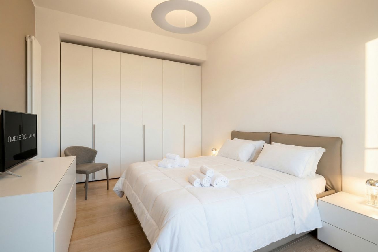 Ein Hotelzimmer mit einem Bett, einem Fernseher, einem Sessel und einem Kleiderschrank.