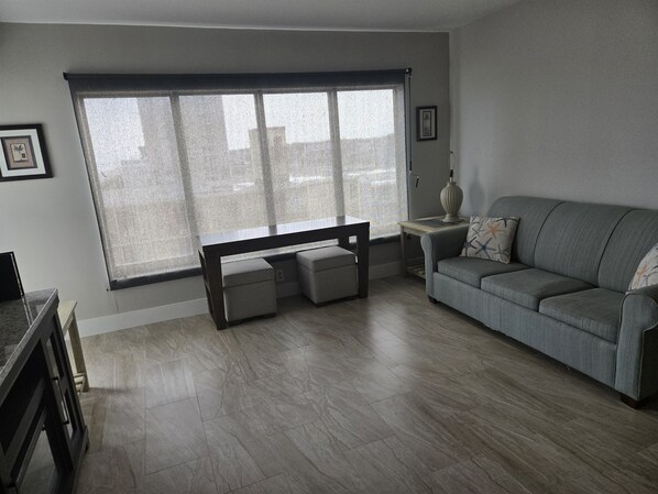 A living room with a grey sofa, a bench, and a table. - Sunset Palace Perfect Beach Getaway: Stunning Updates & Unbeatable Convenience! (Myrtle Beach)