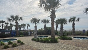 A pool area with palm trees, a sign indicating no lifeguard on duty, and a view of the ocean. - Sunset Palace Perfect Beach Getaway: Stunning Updates & Unbeatable Convenience! (Myrtle Beach)