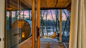 Une cabane en bois avec une porte en verre donnant sur une terrasse qui offre une vue sur un lac.