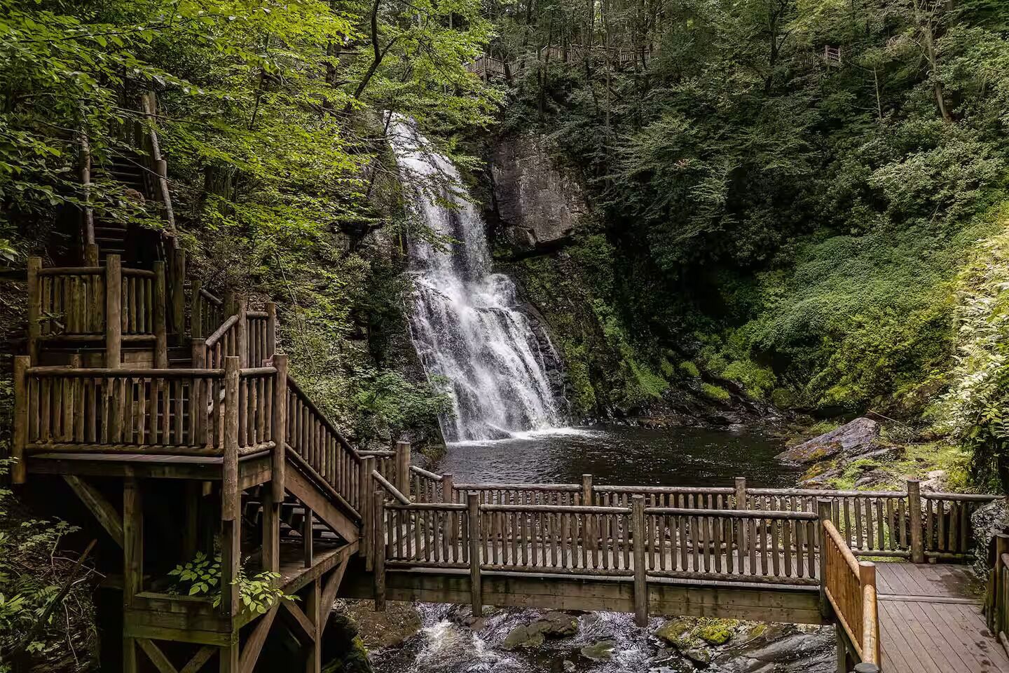 Una terraza de madera con una cascada al fondo.