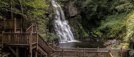 Una terraza de madera con una cascada al fondo.
