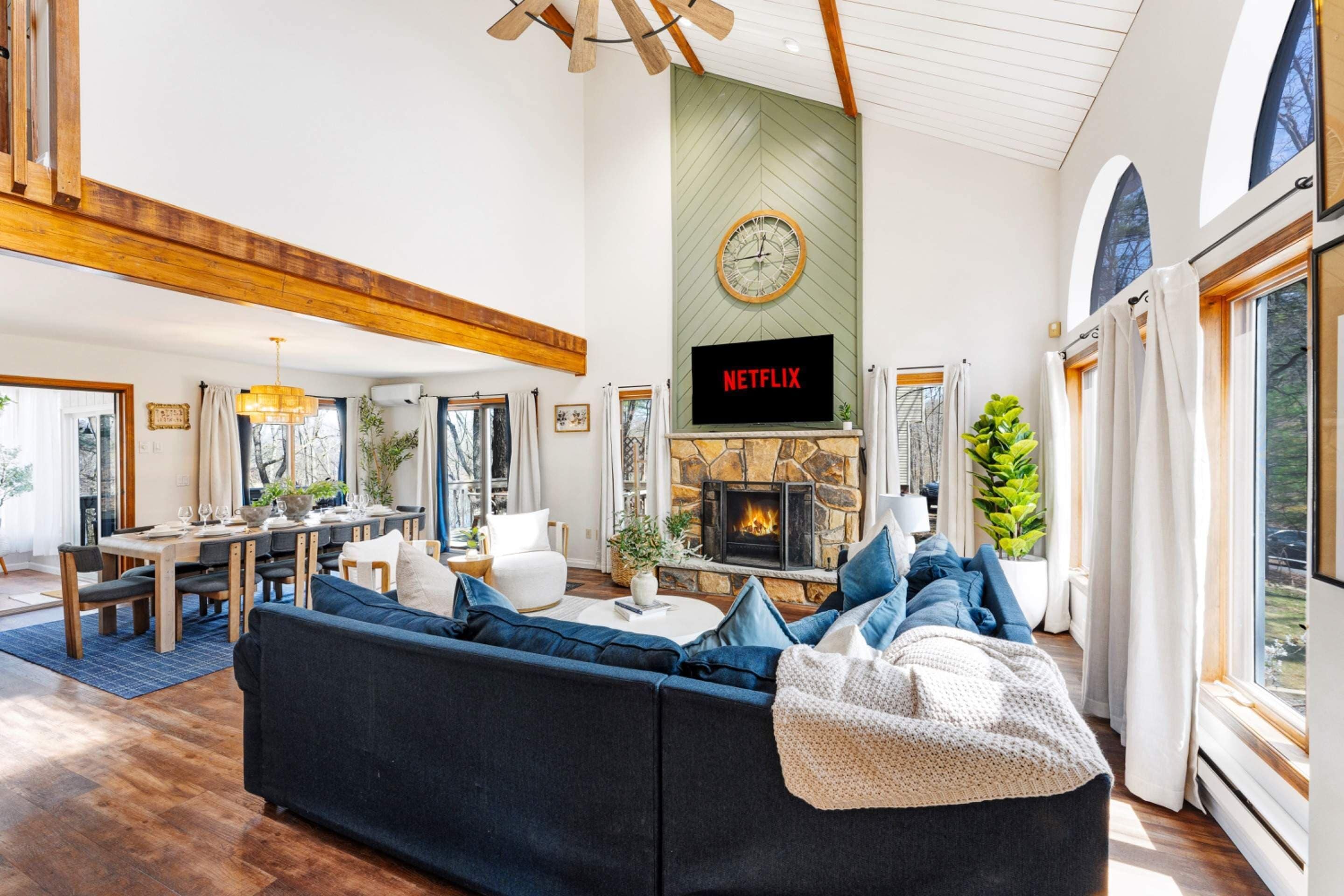 Un salón espacioso con chimenea, comedor y un amplio ventanal con vistas al exterior.