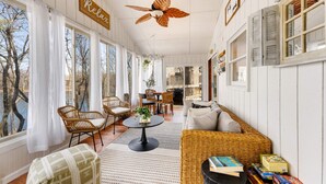 Une pièce confortable avec un ventilateur de plafond, des meubles en osier et une vue sur l’extérieur.