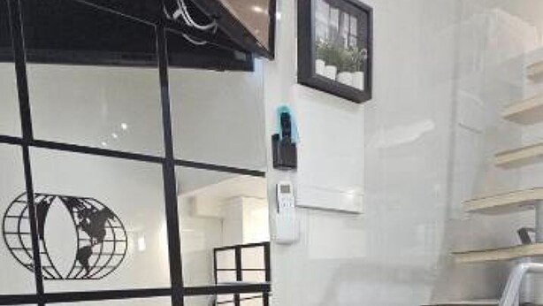 A modern hotel room with a glass partition, a bed, a staircase, and a framed picture on the wall.