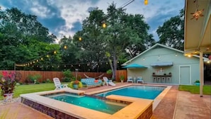 Ein Garten mit Swimmingpool, Liegestühlen und Lichterketten.