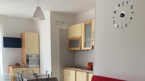 A compact living space with a dining area, kitchenette, and a red sofa. - Twins Apartment - Rodi Garganico (Rodi Garganico)