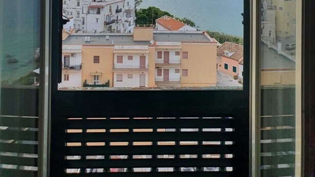 A view from a window overlooking a coastal town with buildings and the sea. - Twins Apartment - Rodi Garganico (Rodi Garganico)