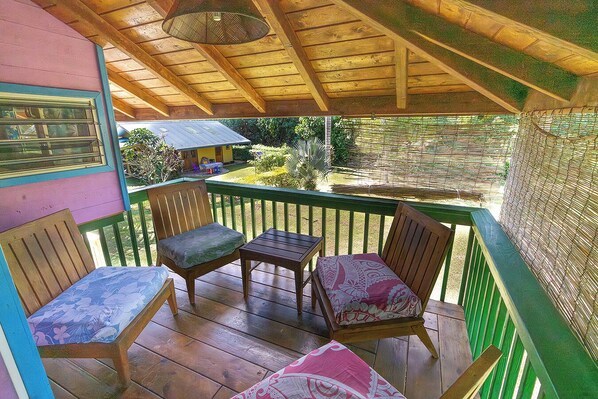 A covered outdoor area with wooden furniture, a table, and chairs. - Fare Manu (Moorea-Maiao)