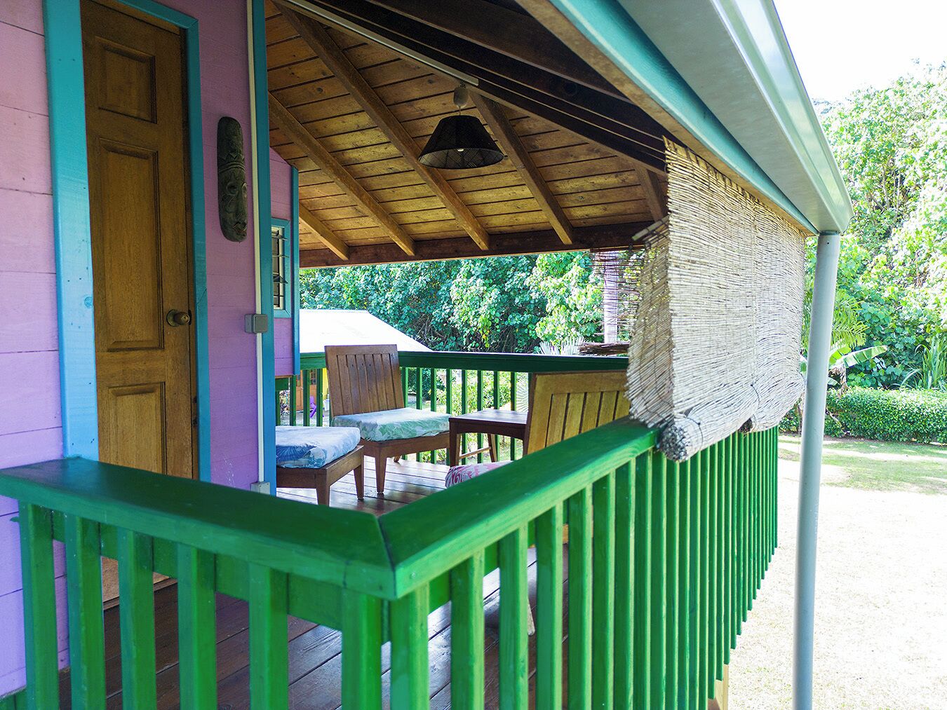 A wooden porch with a green railing, a wooden door, and a bench.
