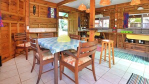 A wooden cabin with a dining area, kitchen, and a large window. - Fare Manu (Moorea-Maiao)