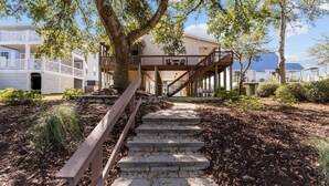 A staircase leading to a wooden deck with a view of a two-story building. - Charming 3BR, 2BA Canal-Front Getaway with Kayaks in Oak Island, NC! (Oak Island)