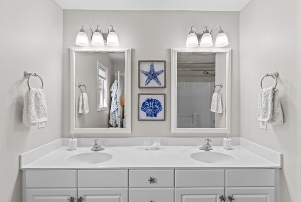 A bathroom with two sinks, a large mirror, and decorative starfish and shell artwork. - Charming 3BR, 2BA Canal-Front Getaway with Kayaks in Oak Island, NC! (Oak Island)