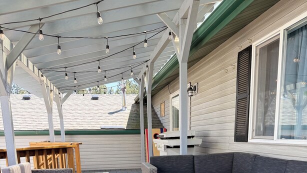 A covered outdoor seating area with wicker furniture, a fire feature, and string lights. - SILVERWOOD•Hot Tub•Lake Fun•Family Friendly•CLEAN! (Hayden)