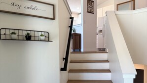 A staircase with white walls and wooden steps, a mounted shelf with potted plants, and a wall-mounted sign with text. - SILVERWOOD•Hot Tub•Lake Fun•Family Friendly•CLEAN! (Hayden)