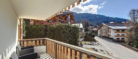 A balcony with a view of a mountain, a road, and buildings.