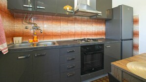A modern kitchen with dark cabinets, a gas stove, an oven, and a refrigerator. - Holiday apartment with a/c (Pula)