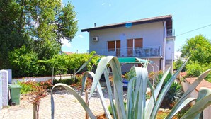 A two-story building with a balcony, surrounded by greenery and a cobblestone path. - Holiday apartment with a/c (Pula)