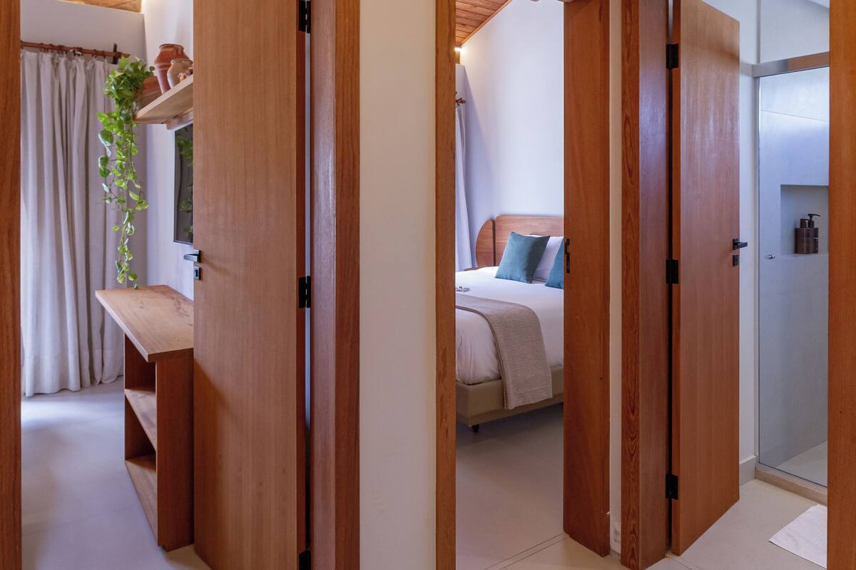 A hallway with wooden doors leading to a bedroom and a bathroom.