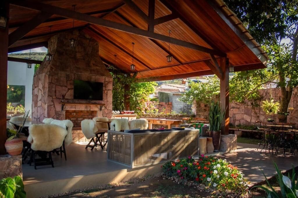 An outdoor patio with a stone fireplace, seating area, and a TV mounted on the wall.